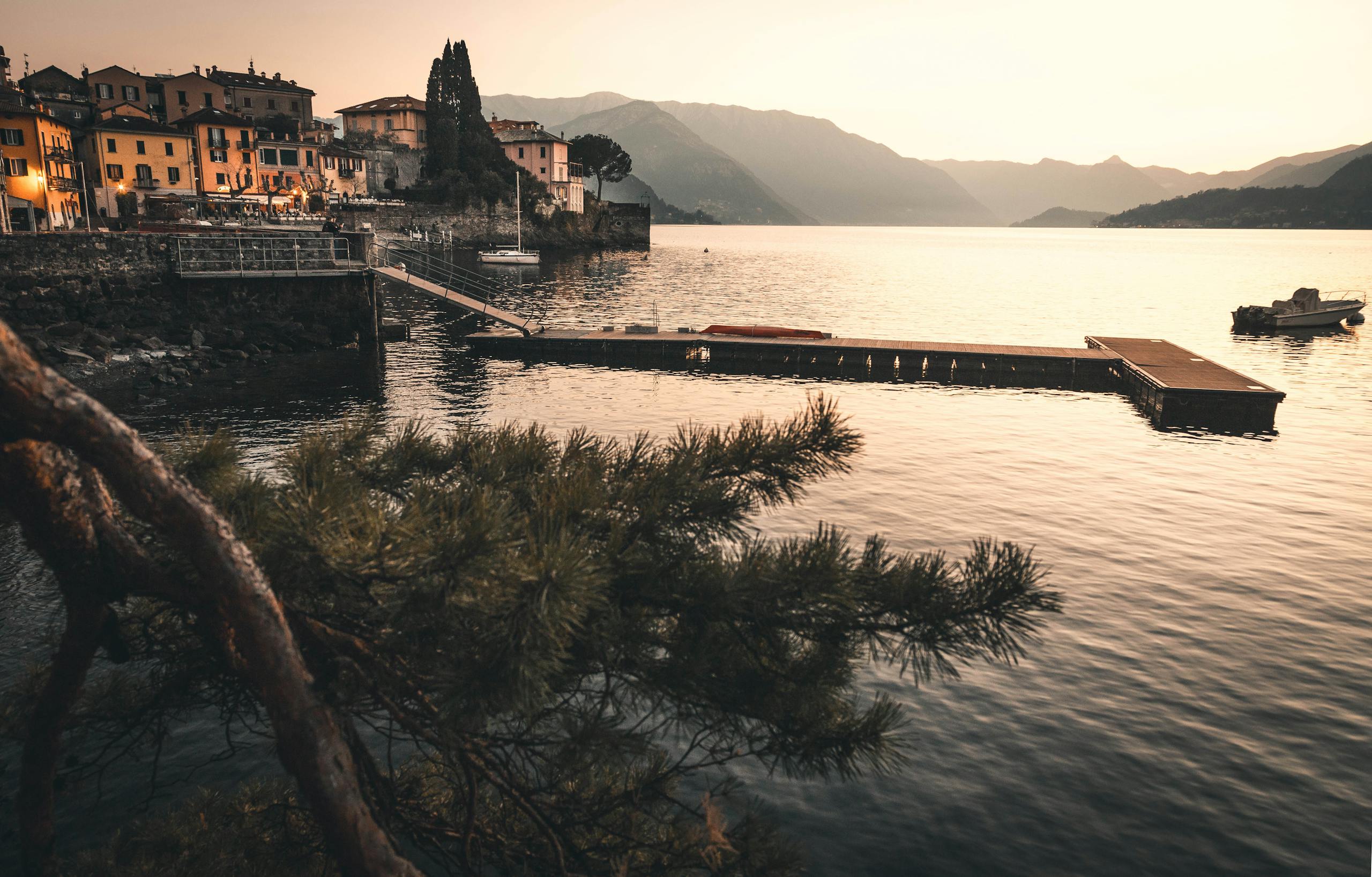 Tranquil sunset over Lake Como with picturesque village and dock.